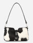 Black and white cowhide handbag with a visible brand logo on a light gray background