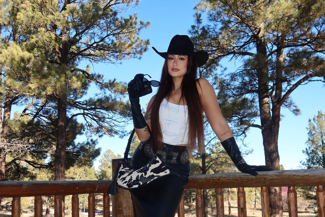 Woman carrying a Hyna natural cowhide bag in an open western American landscape
