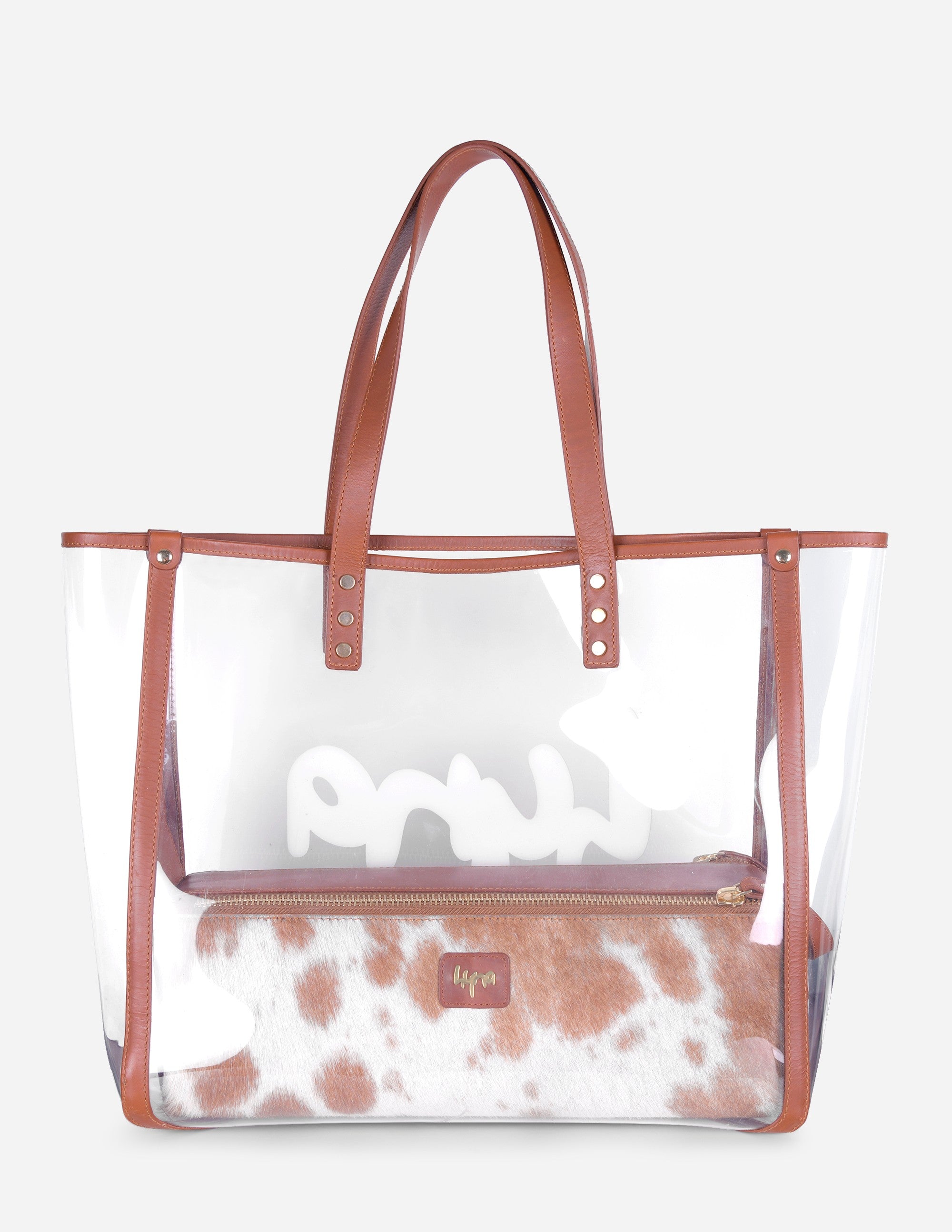 Leather clear tote bag with brown leather handles and cow print interior on a white background